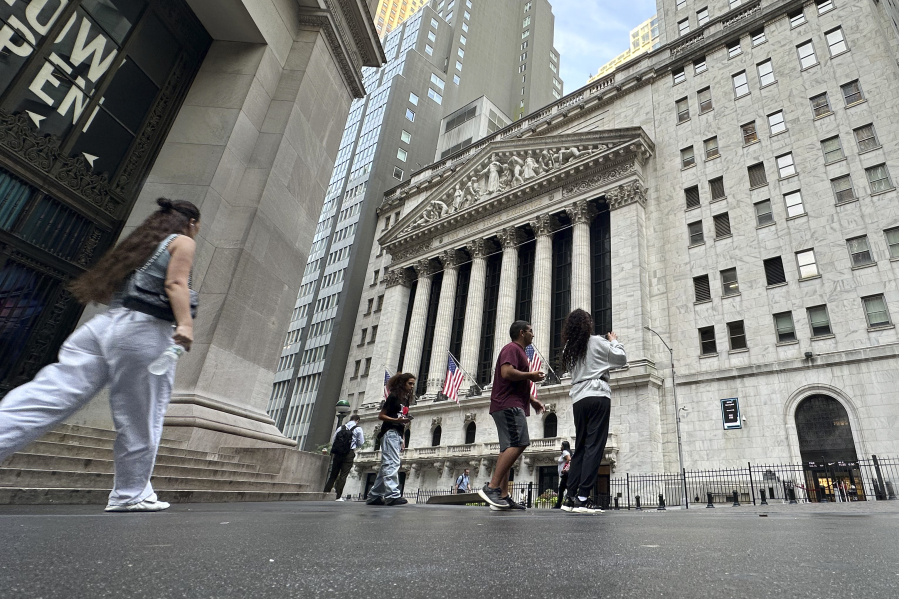 FILE - People pass the New York Stock Exchange July 10, 2024, in New York. World shares began trading mixed on Monday, July 15, 2024, after China reported that its economy expanded at a lower-than-forecast 4.7% annual pace in the last quarter.