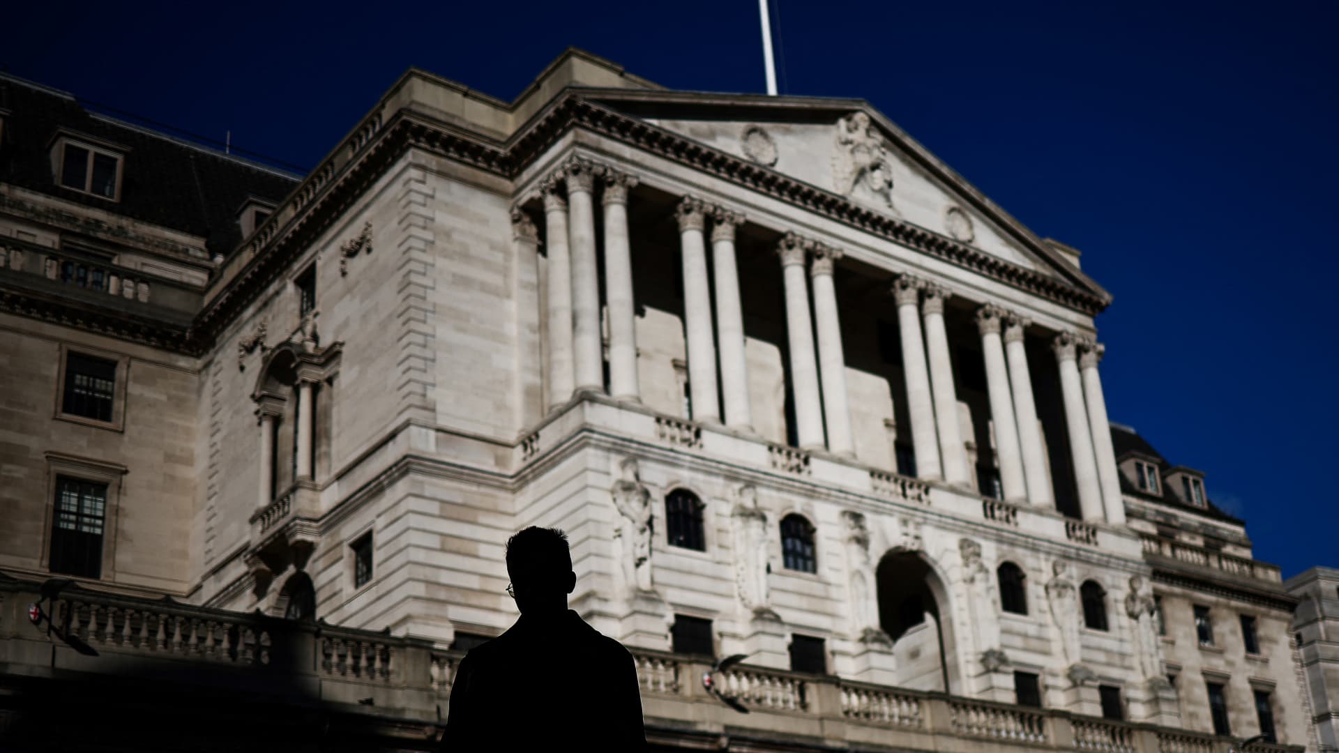 A pedestrian crosses the streets in front of The Bank of England illuminated by a ray of sunlight, in central London, on February 12, 2024.