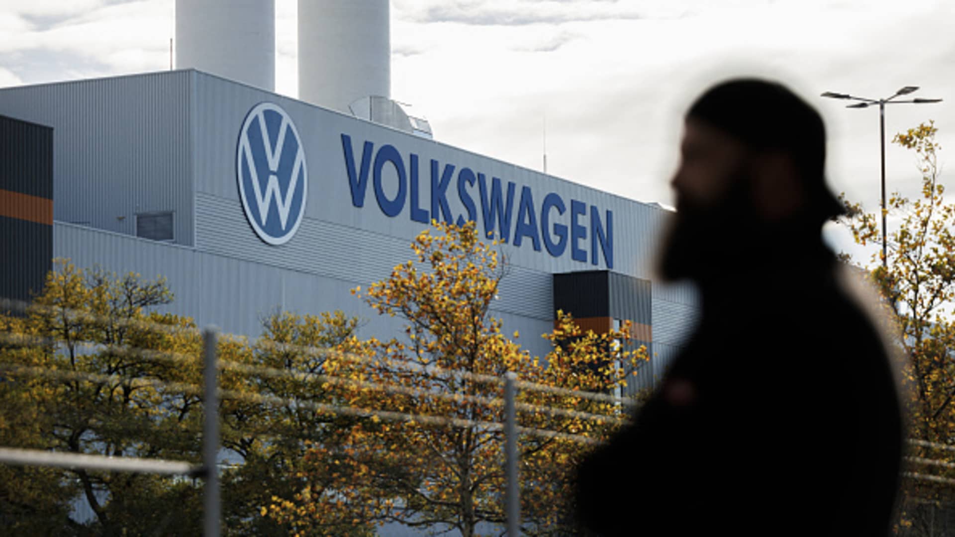 An employee of the Volkswagen plant in Zwickau stands next to the VW logo on the factory premises during an information event organized by the Works Council of Volkswagen Saxony in Zwickau, eastern Germany, on October 28, 2024.